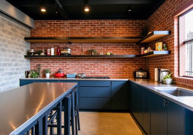 Industrial-style kitchen with exposed brick, stainless steel benchtops, and open shelving in Fitzroy.