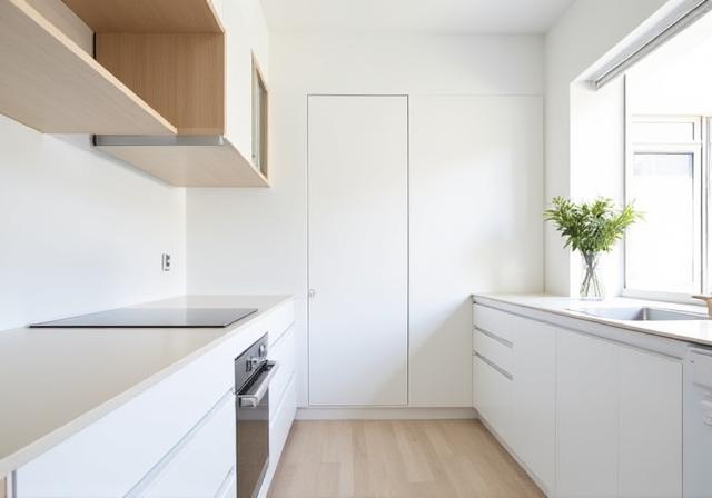 Minimalist kitchen with integrated appliances, flat-panel cabinets, and a seamless white counter in South Yarra.