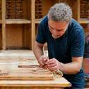 A craftsman working on a piece of kitchen cabinetry in a workshop.